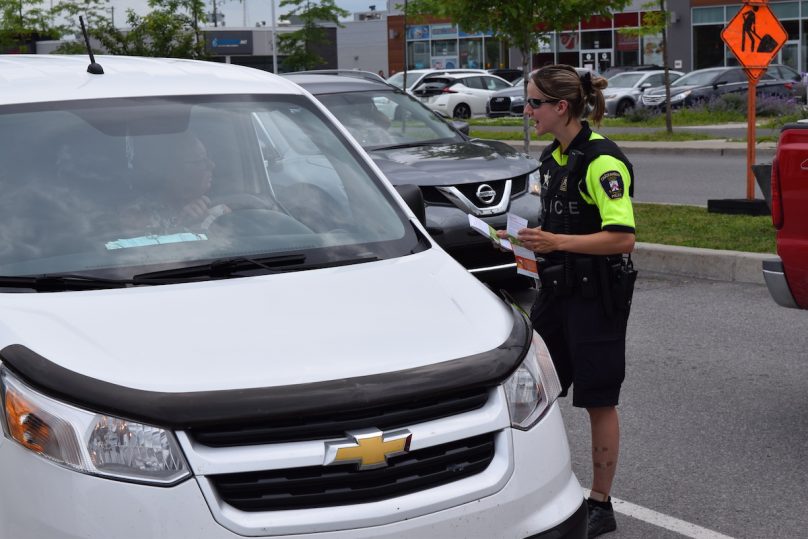 agent police Chateauguay avec automobiliste pour campagne securite Pas de cell au volant photo MRC